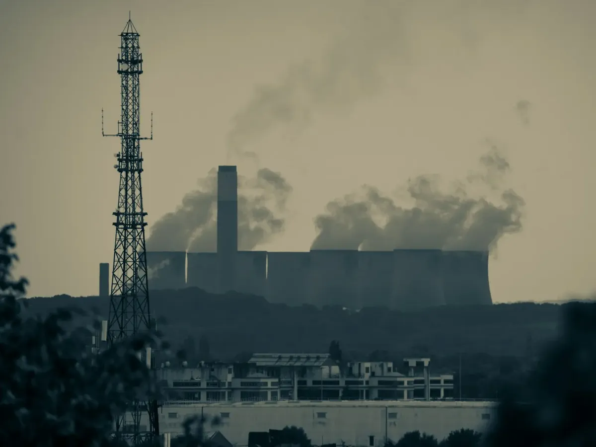 smoke billows from the stacks of industrial buildings