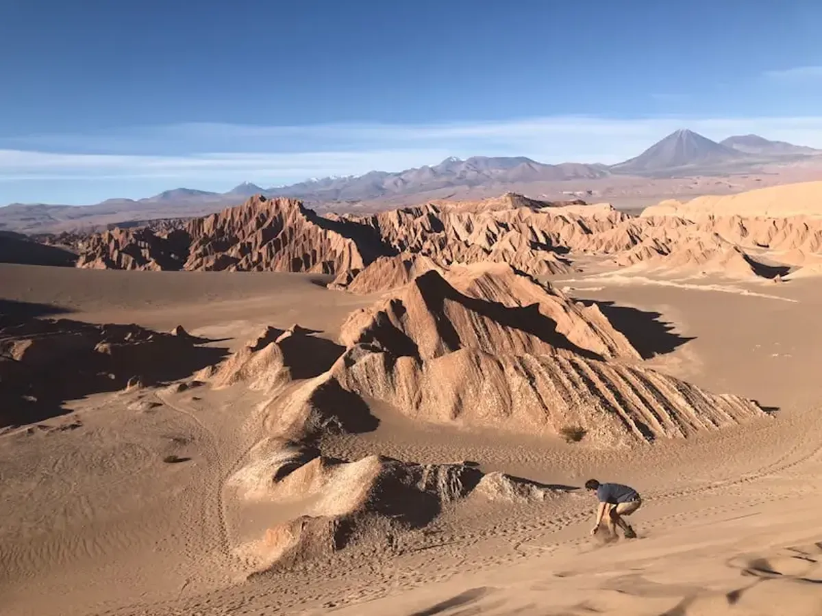 A person riding a camel in the desert during the day.