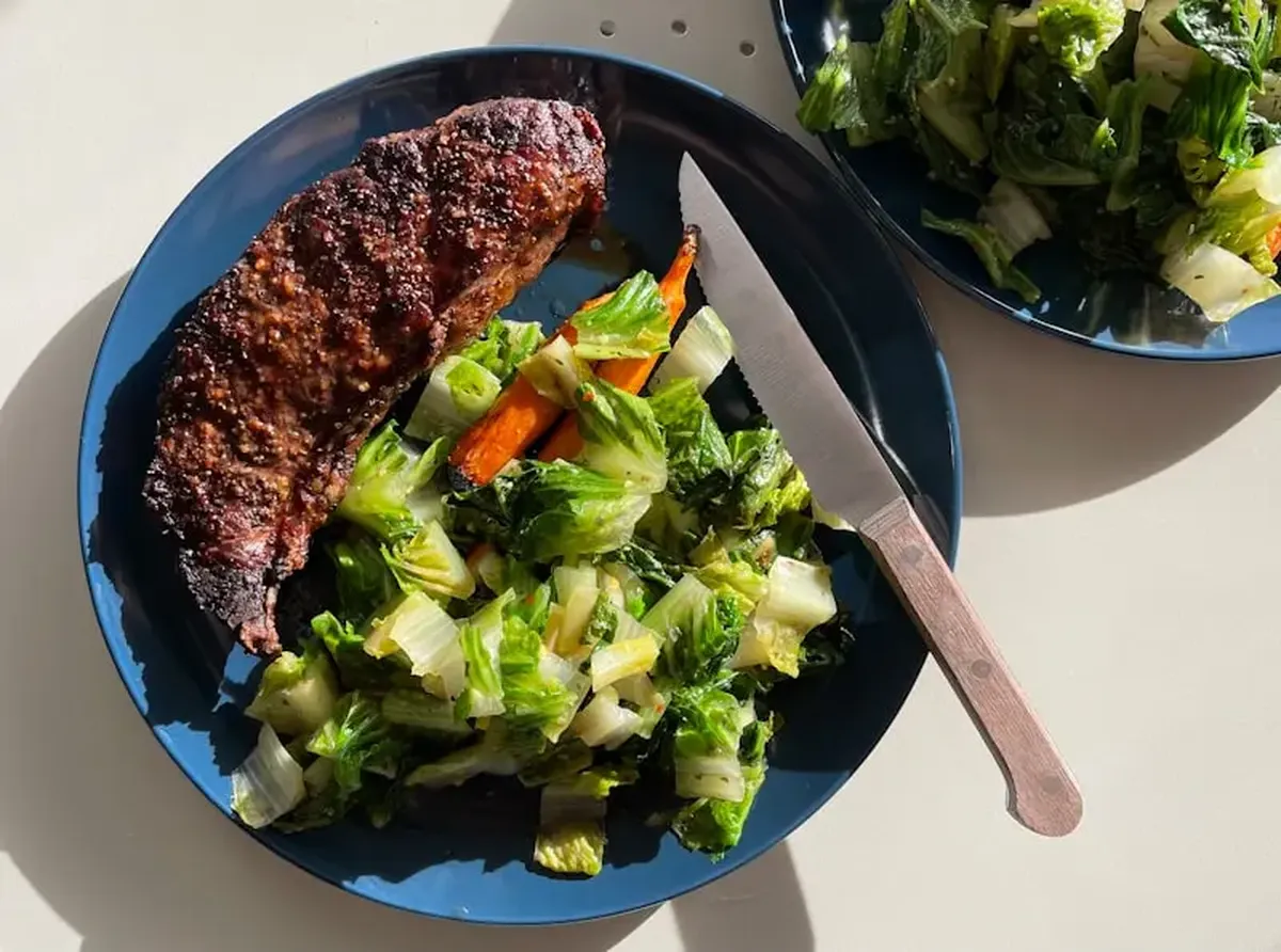 Cooked meat with vegetables on a black plate.