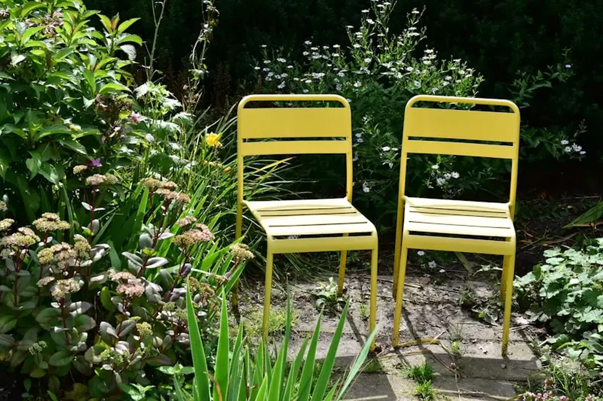 The Small Rules of Hosting: Seating, Flowers, and Relaxation Corners 5 Two yellow chairs sit among the garden plants.