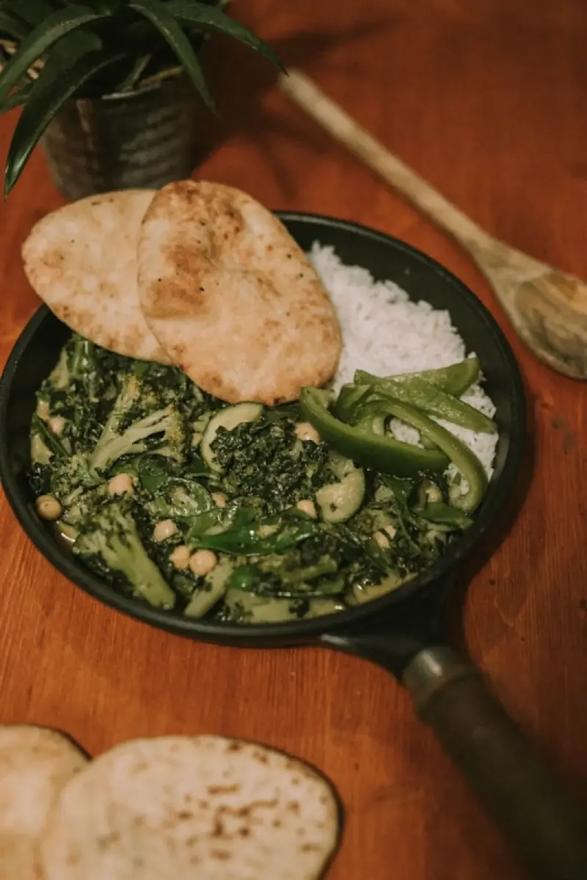 Green vegetables and cooked rice in a black frying pan