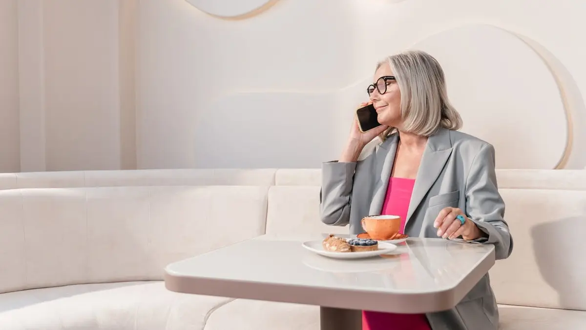 Your Phone Is Teeming with Germs — How to Clean It Safely 4 A woman sitting at a table with food, talking on the phone.