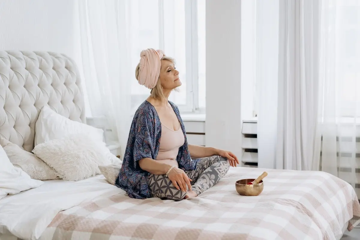 A woman practicing yoga on a bed.