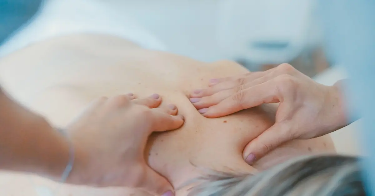 A person massaging a woman's back.
