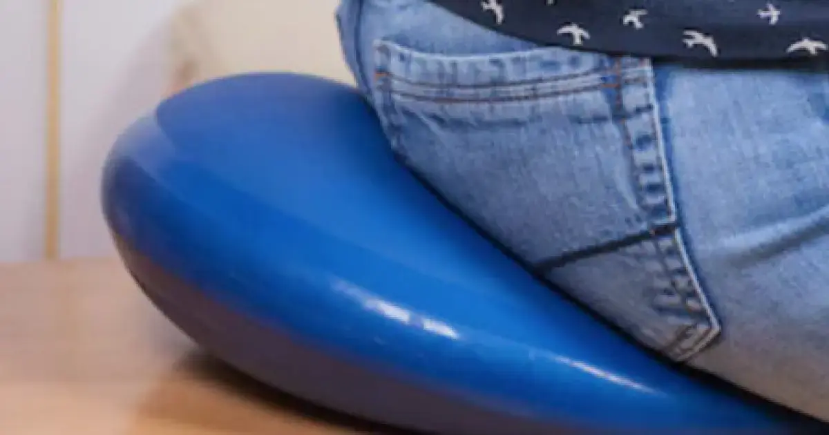 A man with hemorrhoids sitting on a cushion.
