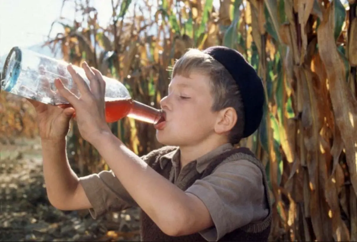 A child drinking wine from a bottle.