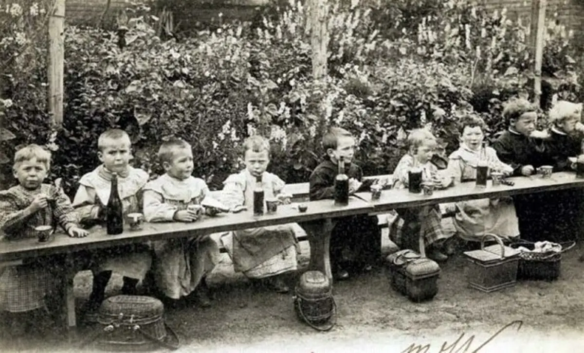Younger students with their own lunch baskets and a bottle of wine, circa 1900.