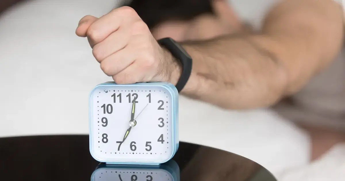 a man reaching for the alarm clock