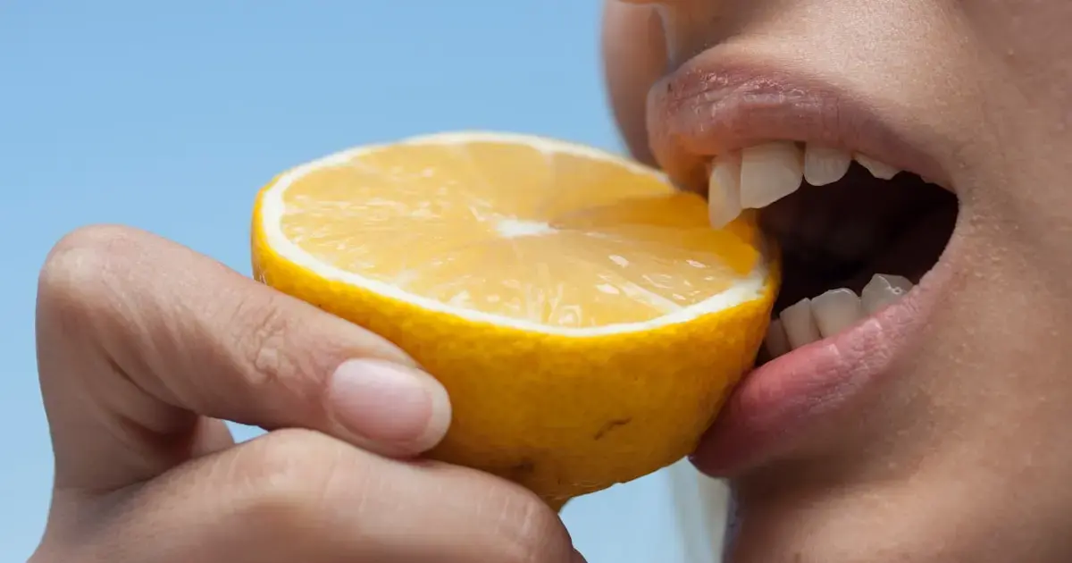 What Your Teeth Really Need: Vitamins and Minerals That Strengthen Them 5 A person eating an orange.