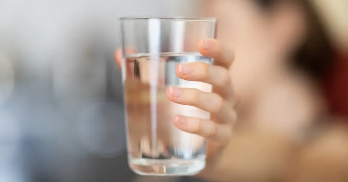 A woman holding a glass of water.