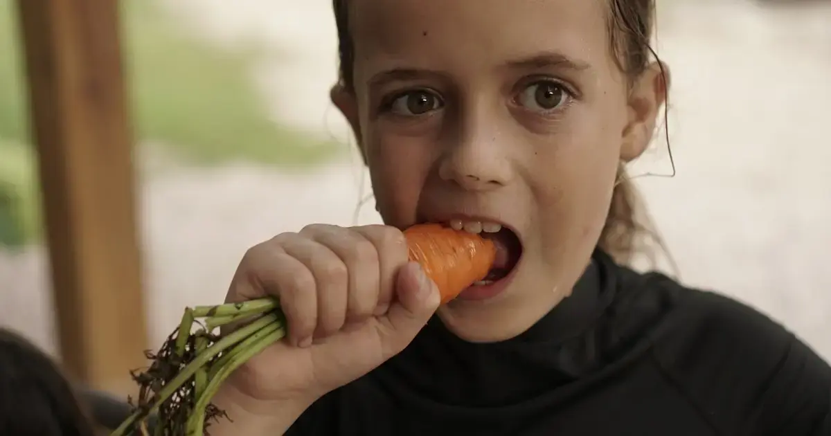 Why vegetarian and vegan kids tend to be lighter and shorter 4 A girl eating a carrot.