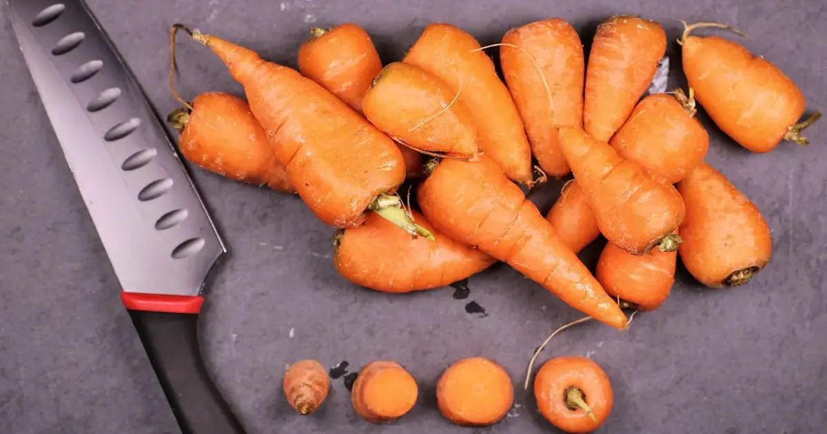 A carrot with a knife on a cutting board.