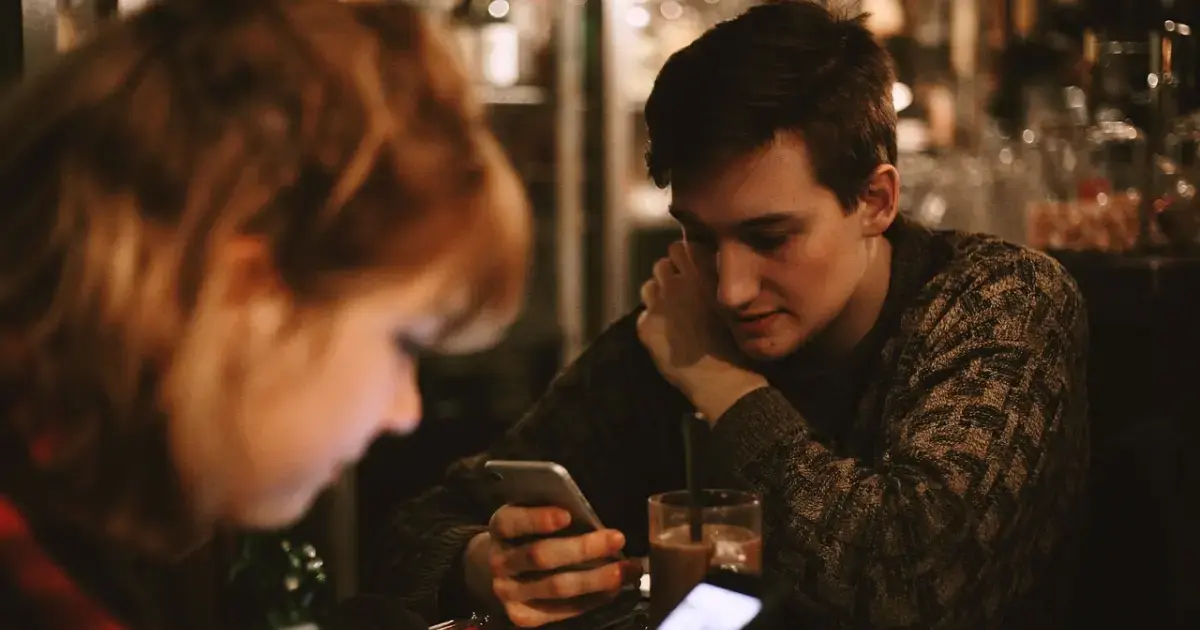 A woman and a man in a café writing text messages