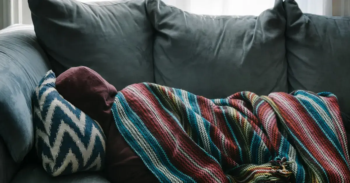 A person wrapped in a blanket, lying in bed.