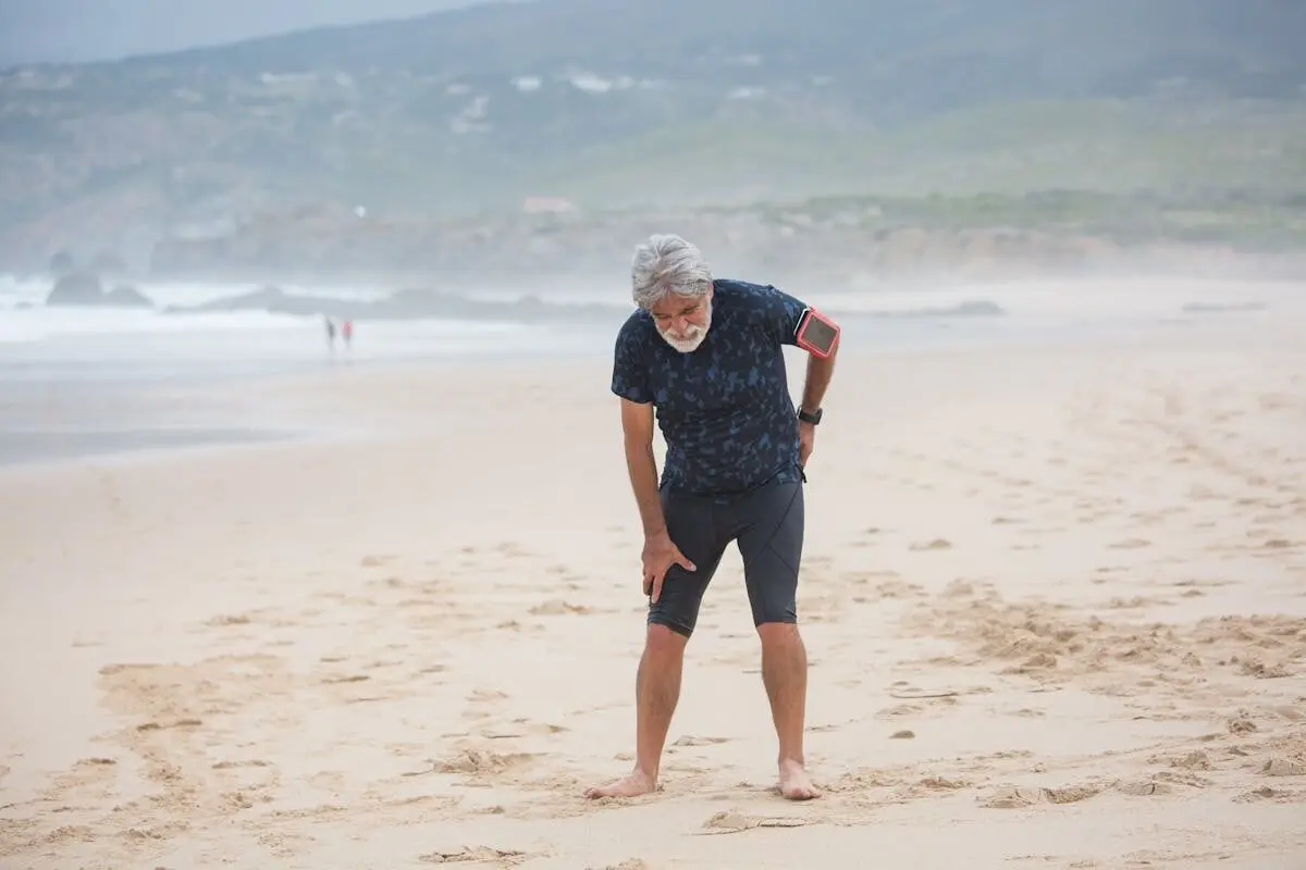 A man doubled over in pain by the sea.