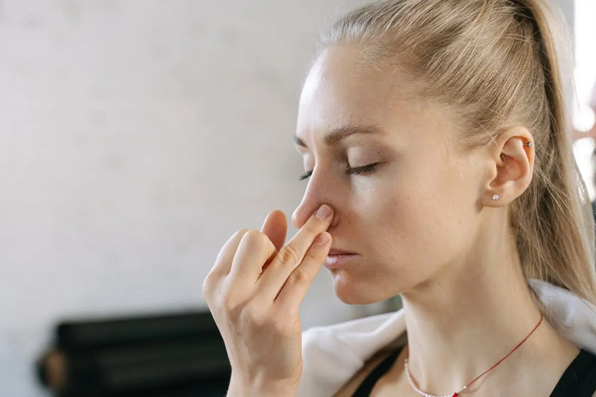 How Bad Smells Harm Your Body and Mind 4 a woman pinching her nose with her fingers