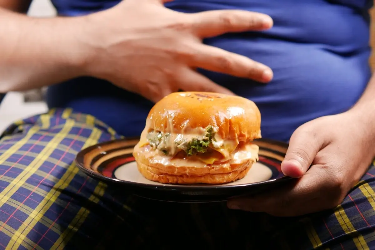 overweight man holding a hamburger