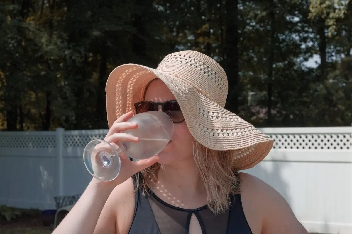 woman in a hat drinking water from a glass