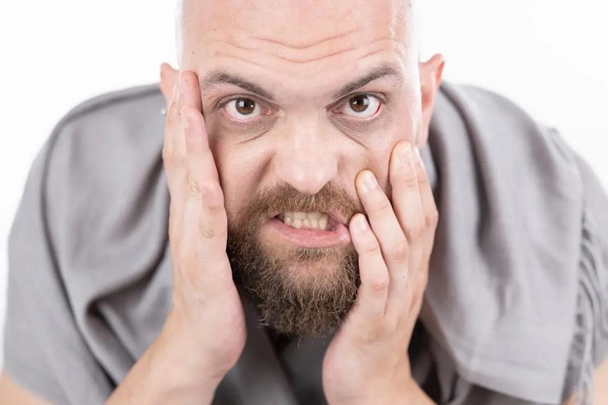 bald man holding his face with his hands